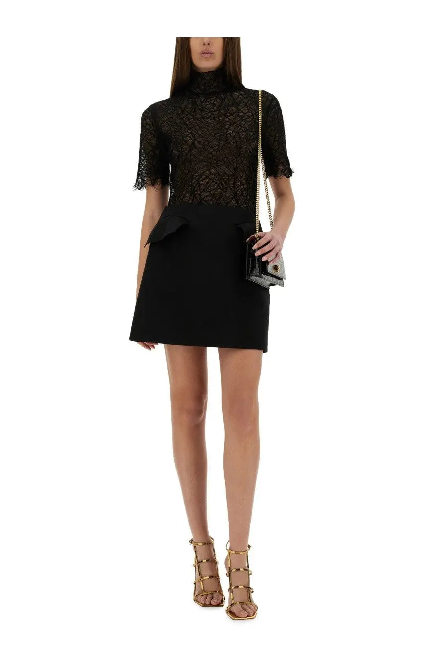 Woman wearing a black lace short sleeve top with peplum hem paired with alexander mcqueen wool mini skirt black