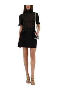 Woman wearing a black lace short sleeve top with peplum hem paired with alexander mcqueen wool mini skirt black