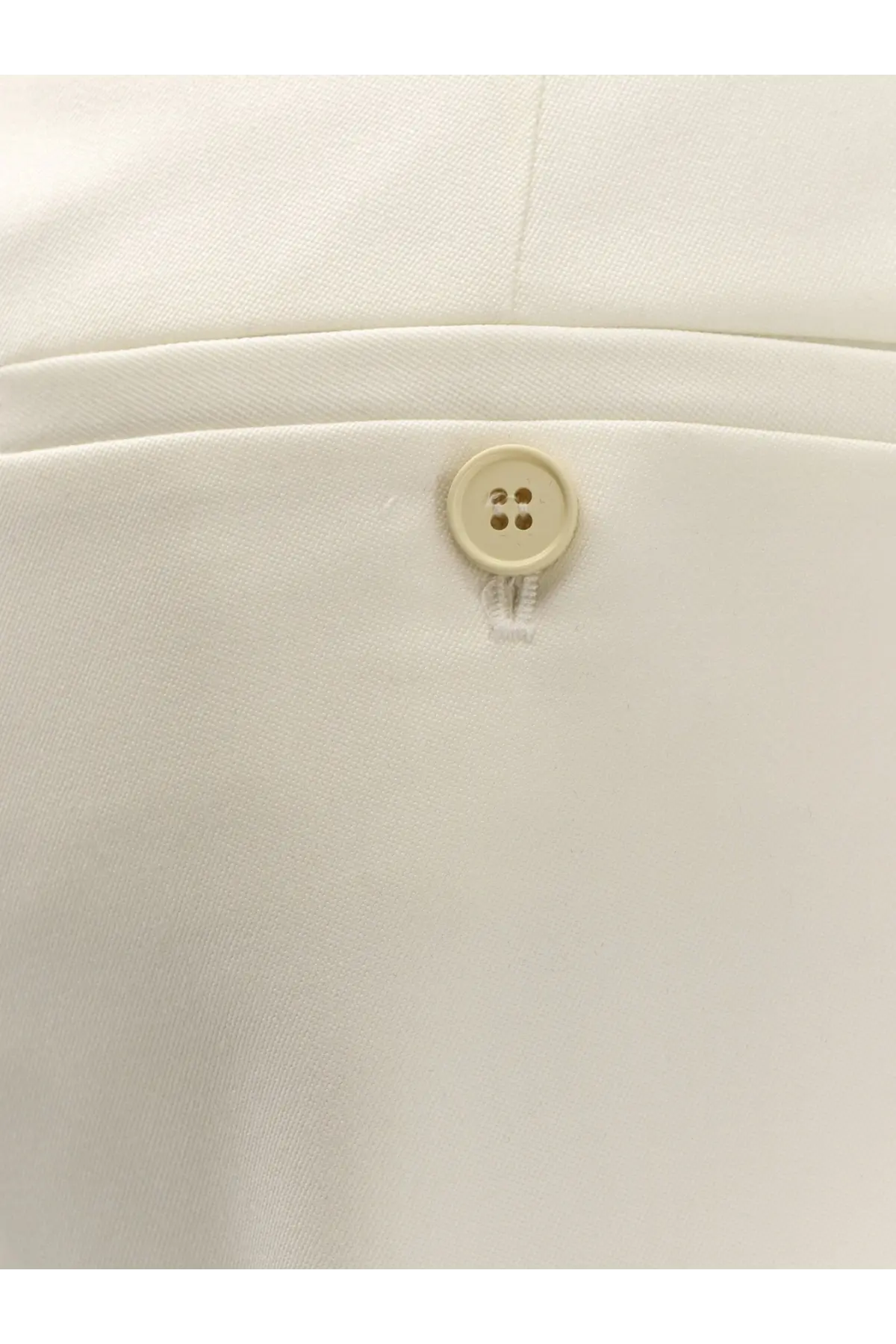 Cream-colored four-hole button on white wool fabric of alexander mcqueen women’s wool trousers