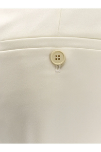 Cream-colored four-hole button on white wool fabric of alexander mcqueen women’s wool trousers