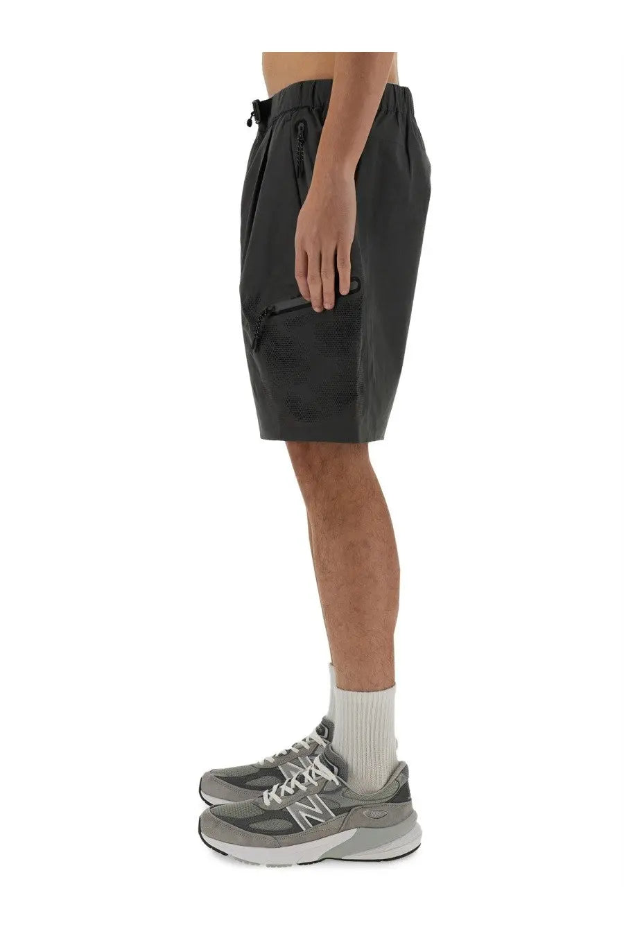 Alpha Industries men’s short laser cut grey shown with black drawstring athletic shorts and gray New Balance sneakers