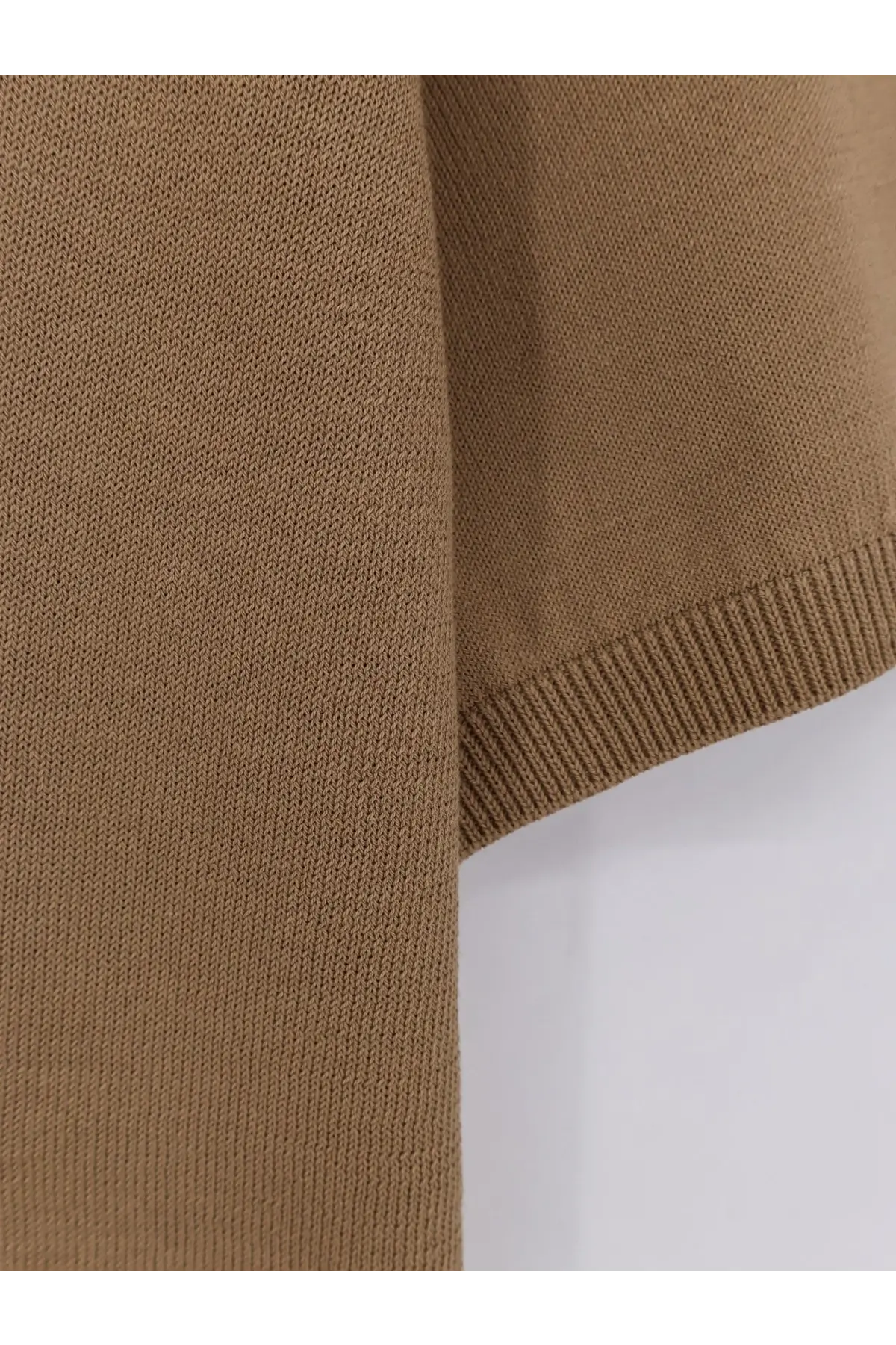 A close-up of a tan knitted fabric sleeve with ribbed cuffs on an alpha-studio men’s cotton polo shirt green