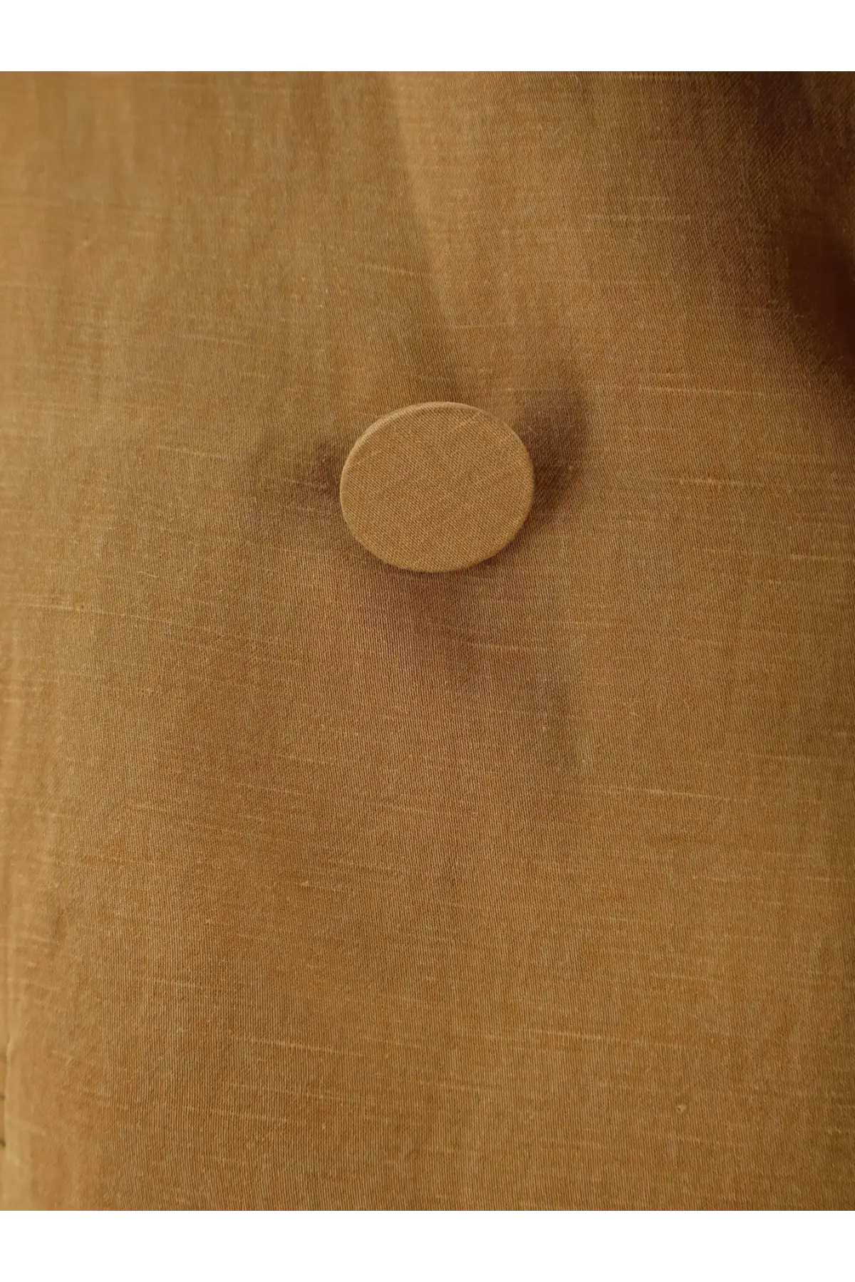 A round tan-colored button with a textured surface on alysi women’s double breasted lyocell and linen blazer