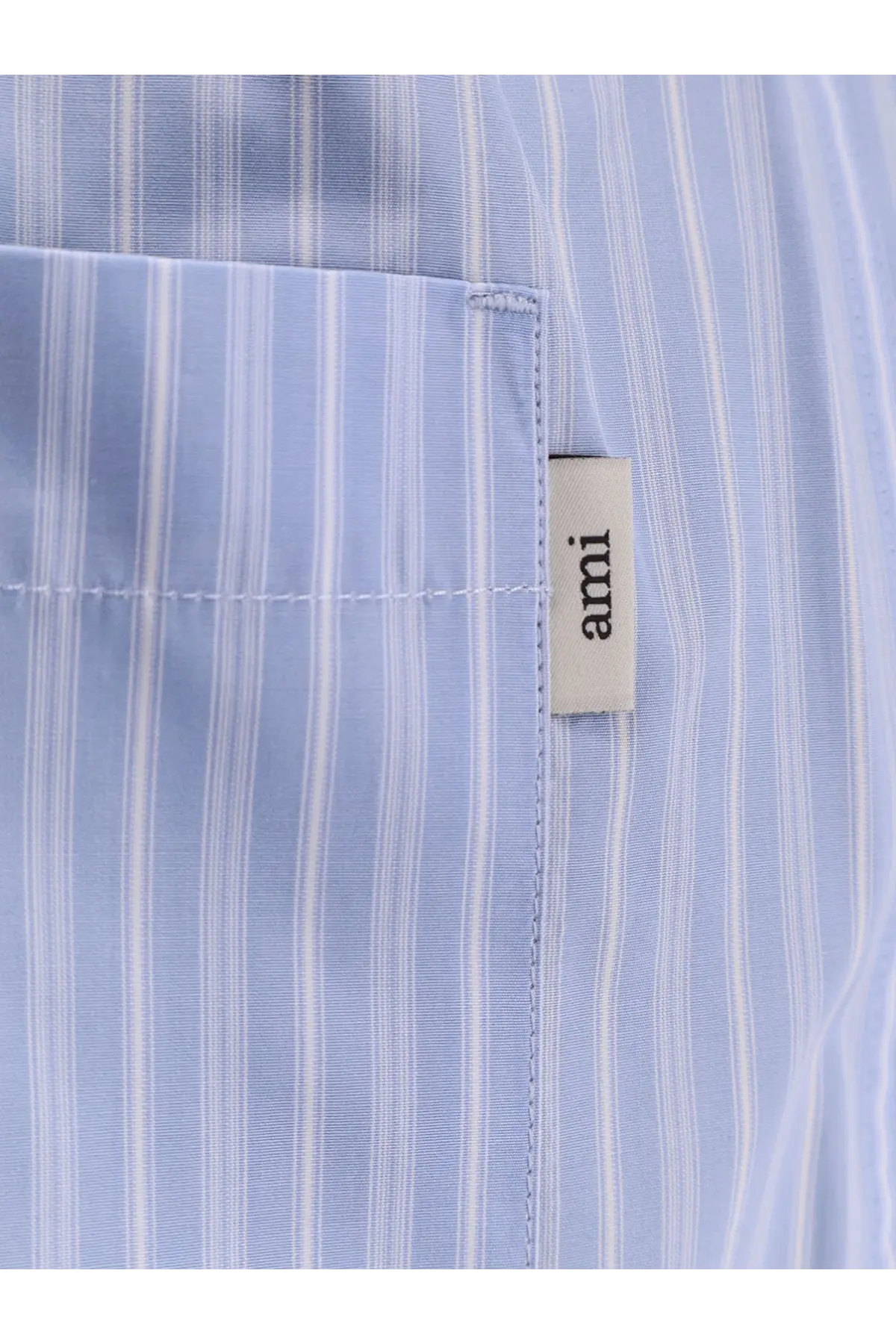 Light blue and white striped cotton shirt with beige ami brand tag paired with ami paris men’s blue cotton bermuda shorts