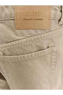 Beige denim Ami Paris men’s cotton trousers with tan leather brand patch embossed ami alexandre mattiussi on back