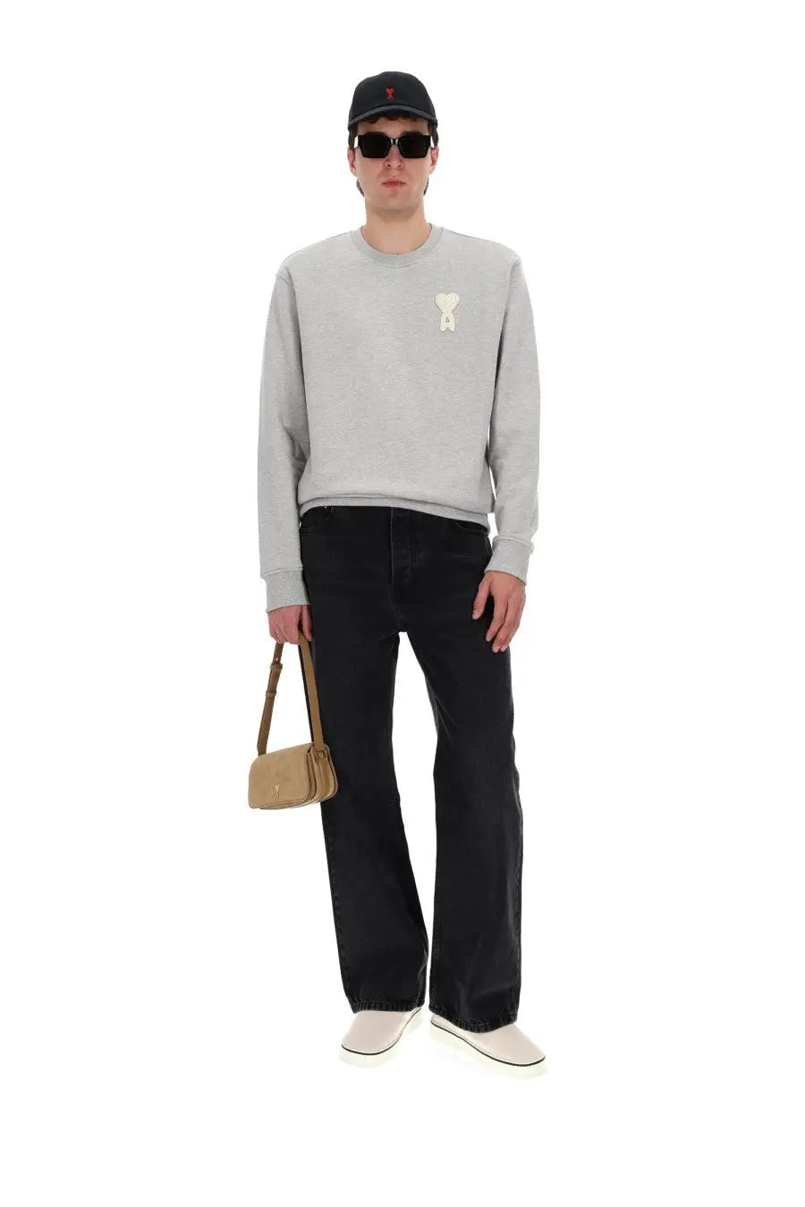 A beige suede crossbody bag with minimalist design and small gold-tone logo paired with ami paris men’s large fit black jeans