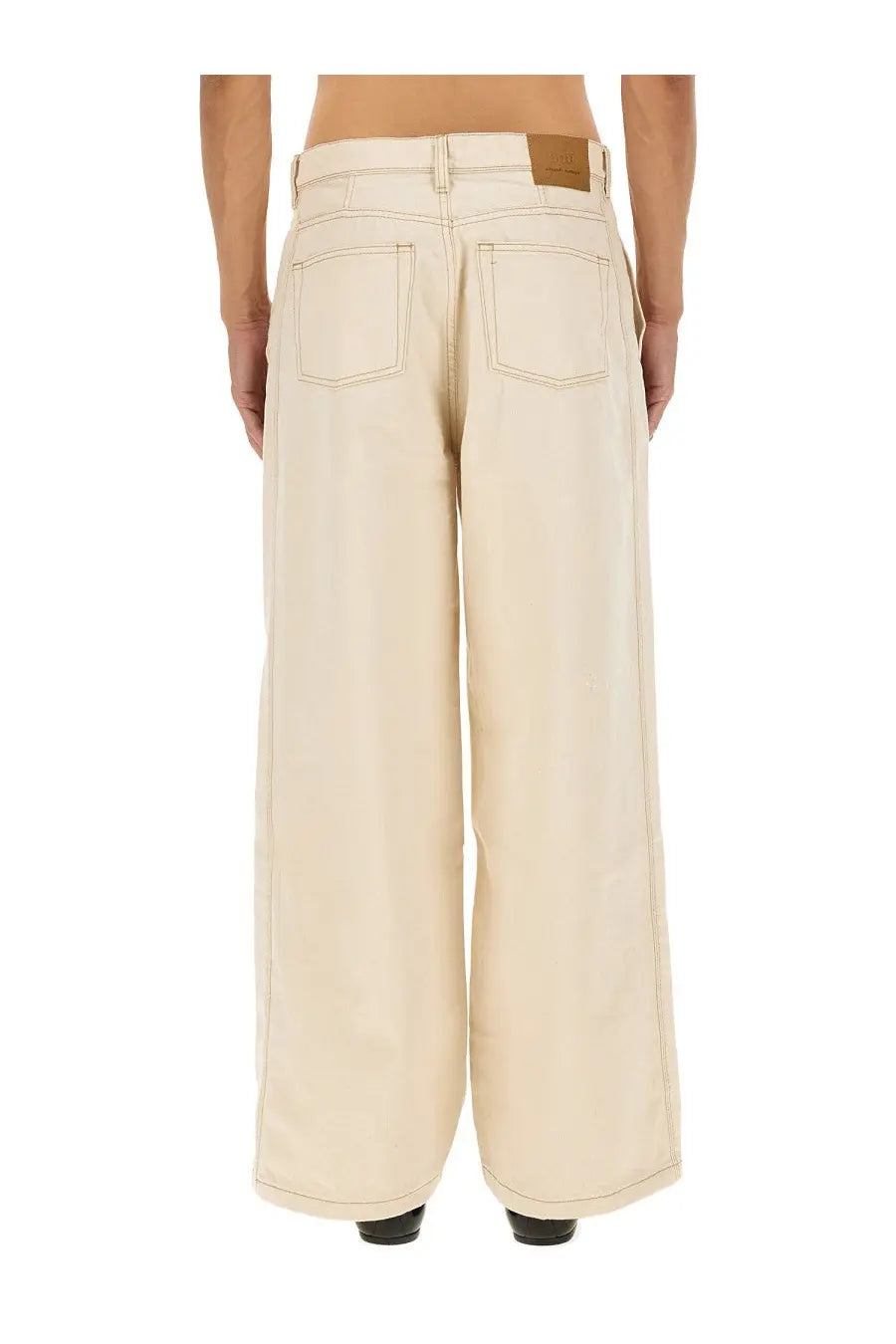 Cream-colored wide-leg denim trousers with classic back pockets and brown leather patch at the waistband back view