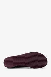 The sole of a dark burgundy rubber sole with vertical ridges on ami paris men’s leather low top pink sneakers