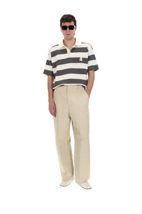 A man wearing a black and white striped short-sleeved polo shirt with an embroidered logo by ami paris