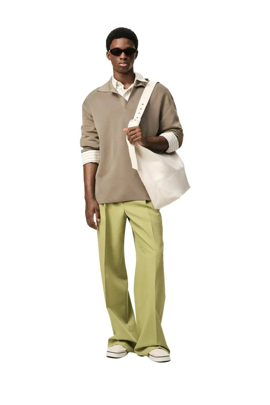 A cream-colored canvas tote bag with white strap and silver hardware styled with ami paris men’s wool blend beige polo shirt