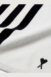 Ami Paris unisex cotton beach towel in white with bold black stripes and a small embroidered heart logo