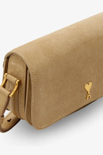 Beige suede crossbody bag by Ami Paris featuring a gold-tone heart-shaped logo clasp and matching hardware