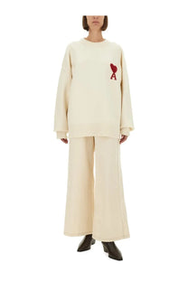 Cream-colored oversized knit sweater with red embroidered heart and letter a paired with ami paris women’s beige jeans
