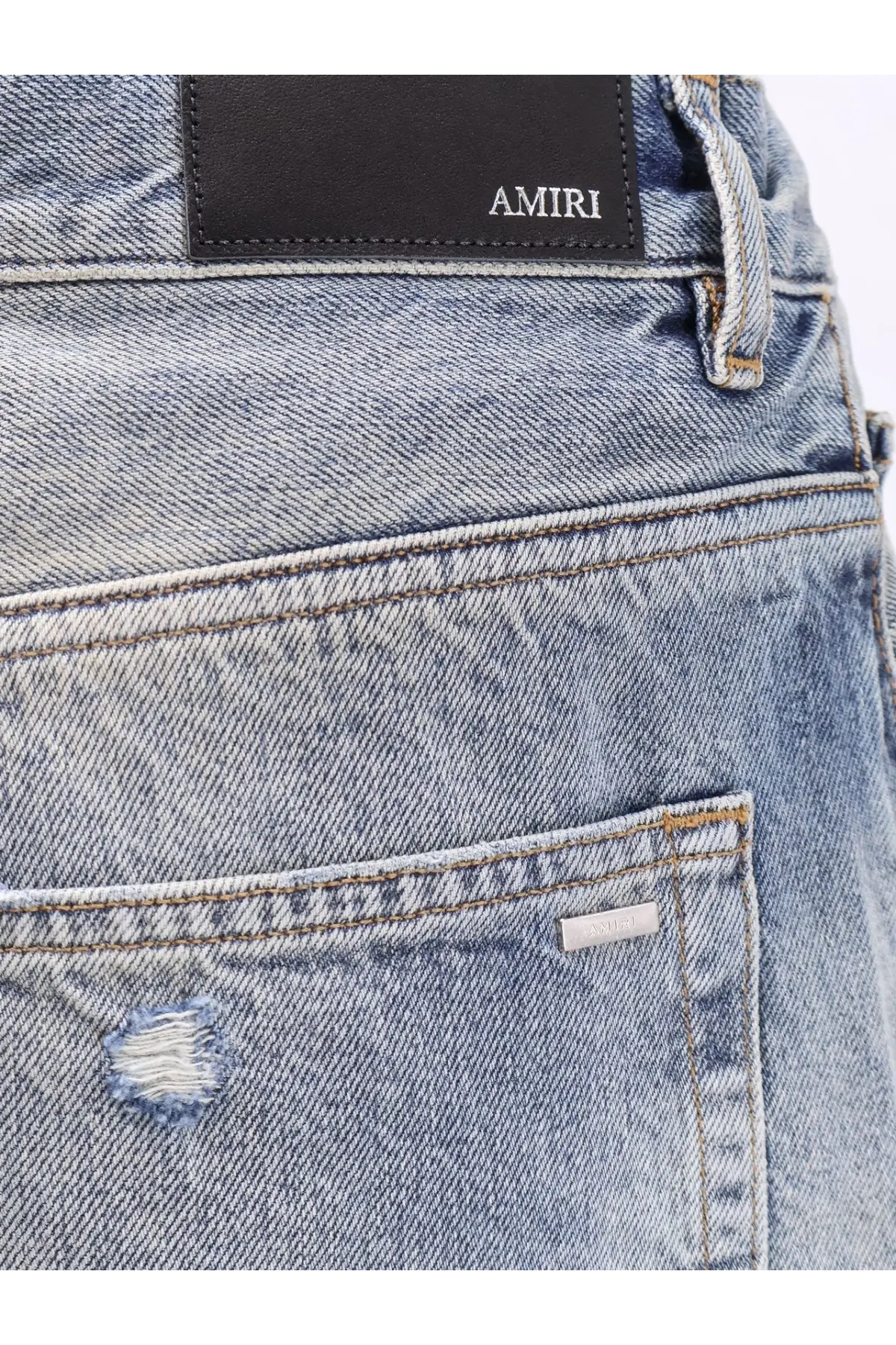 Back side of amiri men’s destroyed effect light-wash denim jeans with distressed patch and brand label on pocket