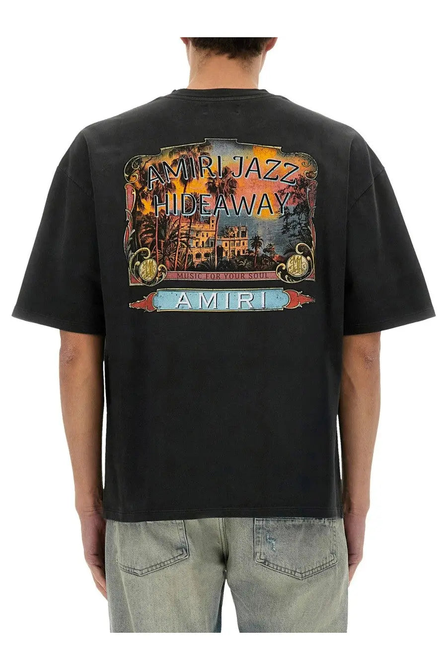 Amiri men’s black t-shirt featuring a vibrant vintage-style tropical hideaway graphic with palm trees and architecture