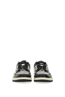 Amiri men’s black low-top sneaker with glossy black and white checkerboard pattern and amiri branding on the tongue