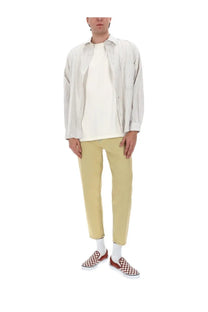 A man wearing amish supplies men’s jeans jeremiah harley beige with light gray striped shirt and red checkerboard shoes