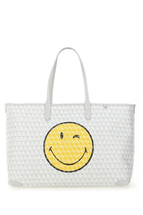 Anya Hindmarch women’s white tote bag with repeating geometric pattern and large yellow winking smiley face on front