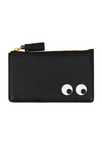 Black leather zippered card case with white googly eyes and gold-tone zipper pull with black tassel by anya hindmarch