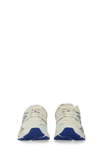 Cream-colored asics unisex gel kayano running shoes with navy blue accents and textured rubber sole front view