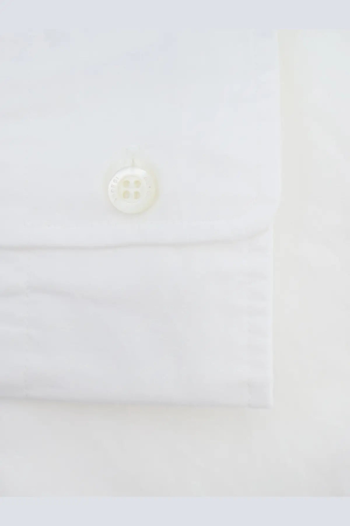 A crisp white cotton button-down shirt cuff with an off-white four-hole button from aspesi men’s fred collection