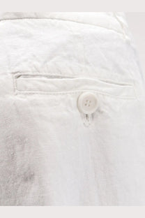 White button with four holes sewn on textured white fabric of Aspesi women’s vissuto linen trousers