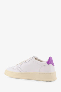Autry women’s medalist low leather sneaker in white with vibrant purple heel tab and cream rubber sole visible from back