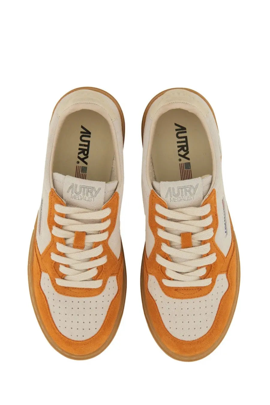 Autry women’s medalist low sneaker in orange and white suede and leather with gum rubber sole visible from front angle