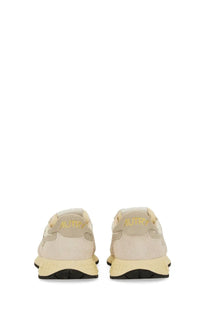 Back view of autry women’s reelwind low sneaker in beige suede and mesh with pale yellow rubber sole and gold branding