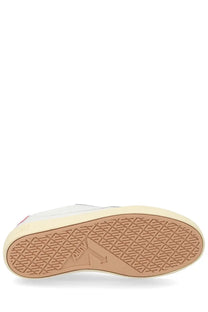 The sole of a white and red autry women’s sneaker windscape low with a tan rubber outsole and embossed logo
