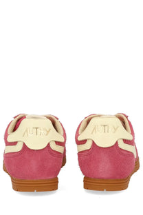 Back view of autry women’s windspin low sneaker in pink suede with cream accents and tan rubber sole showing brand name