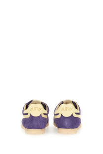 Back view of autry women’s windspin low sneaker in purple suede with cream accents and autry logo on heel