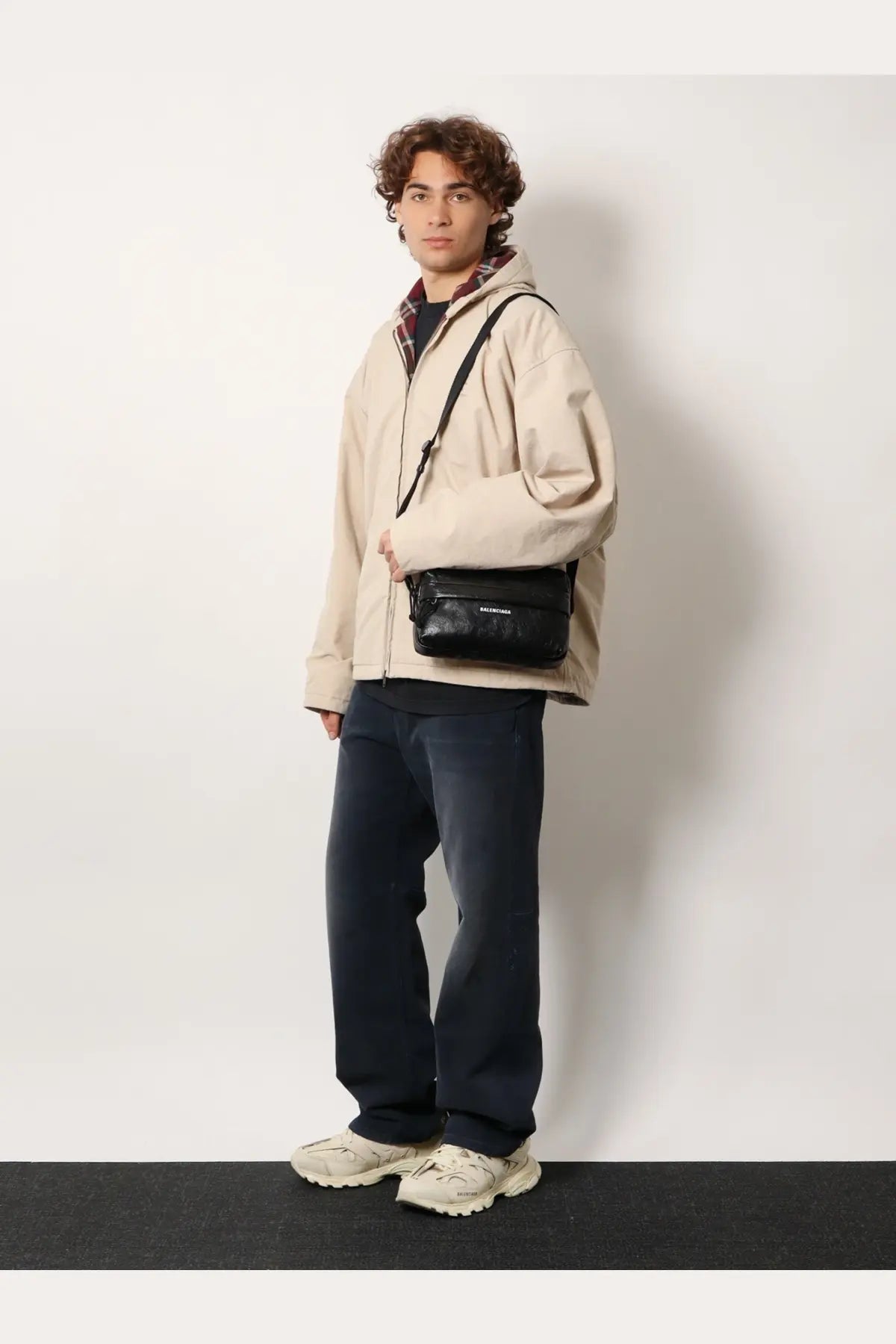 Black textured crossbody bag with sleek minimalist design and subtle branding shown with balenciaga men’s beige cotton blend jacket