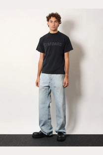 Black short-sleeved t-shirt with standard printed in textured font paired with balenciaga men’s distressed blue jeans