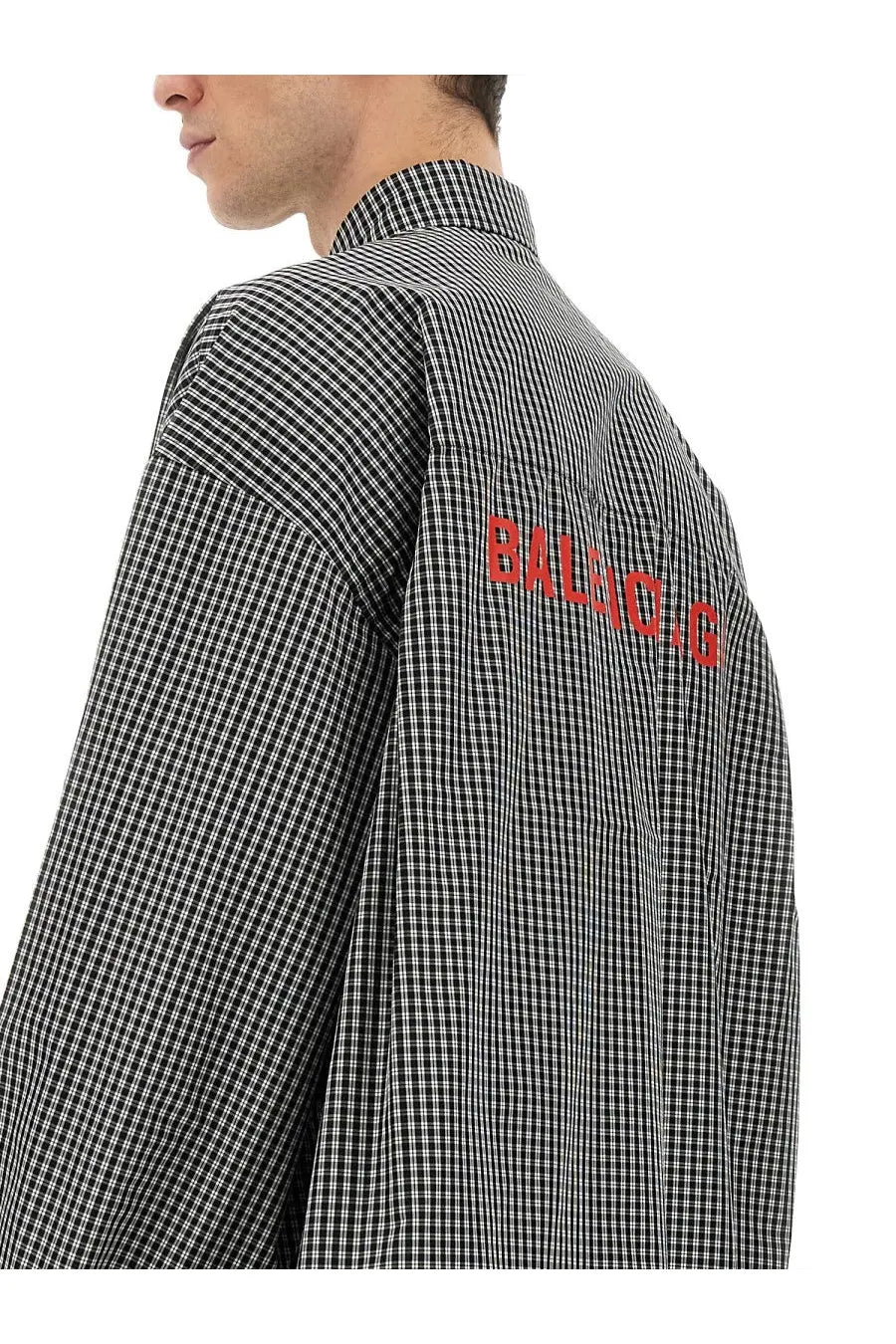 Back view of balenciaga men’s oversize fit shirt in black and white checkered pattern with bold red balenciaga lettering