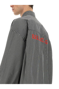 Back view of balenciaga men’s oversize fit shirt in black and white checkered pattern with bold red balenciaga lettering