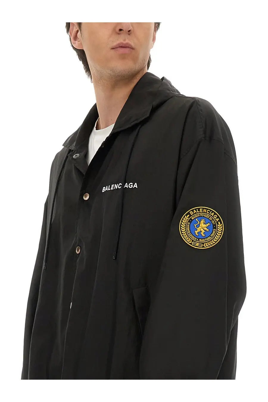 Balenciaga men’s oversized black hooded windbreaker jacket with gold and blue embroidered crest on sleeve
