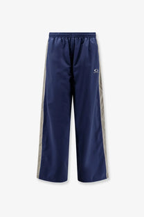 Balenciaga men’s sporty nylon navy blue track pants with silver side stripes and small white logo on the thigh