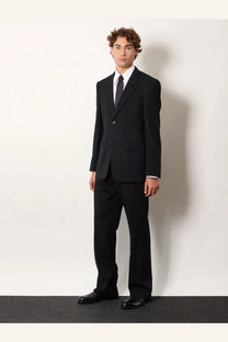 Balenciaga men’s straight fit black cotton trousers paired with a black single-button suit jacket white shirt and dark tie