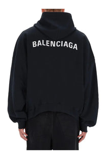 Back side of a black balenciaga men’s sweatshirt hoodie with bold white lettering across the back