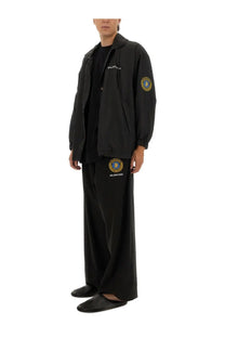 Balenciaga men’s tracksuit pants black with matching hoodie featuring embroidered gold circular logos on chest sleeve and thigh