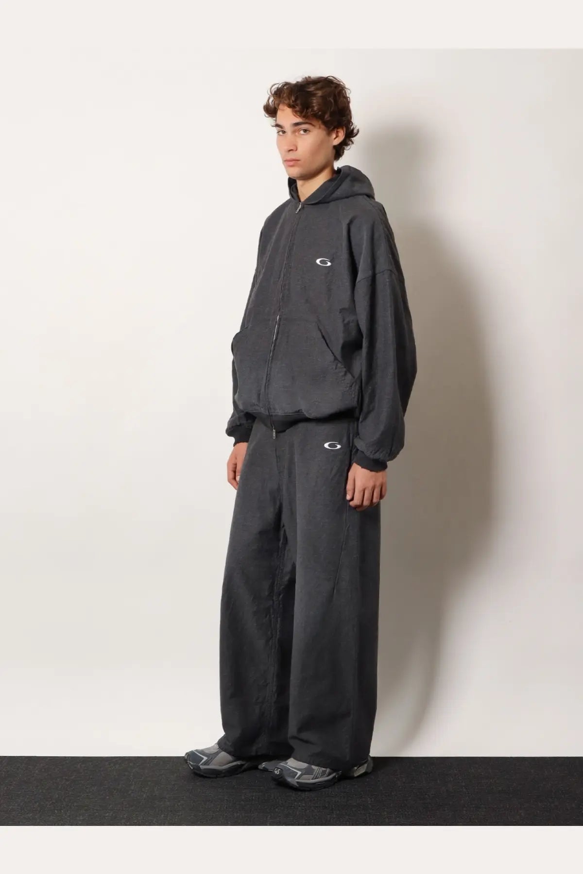 Dark gray oversized hoodie with subtle white logo and matching wide-leg pants featuring relaxed silhouettes
