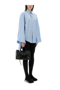 Black glossy balenciaga city bag with silver hardware and frayed detailing shown with balenciaga women’s blue blouse