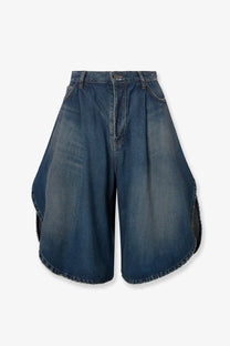 Balenciaga women’s high-waisted cotton bermuda shorts in medium blue wash with flared asymmetrical cut and raw hem