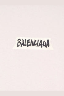 Black handwritten balenciaga logo on torn white paper sticker on balenciaga women’s white cotton shirt