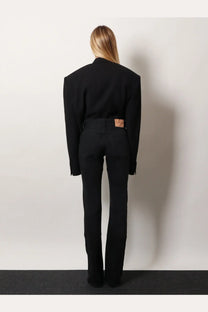 Black tailored blazer with exaggerated shoulders and long sleeves paired with balenciaga women’s black denim trousers