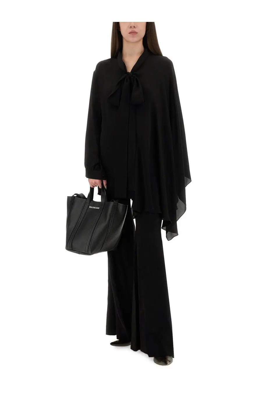 Black balenciaga tote bag with structured silhouette and bold vertical stitching paired with women’s flared pants black