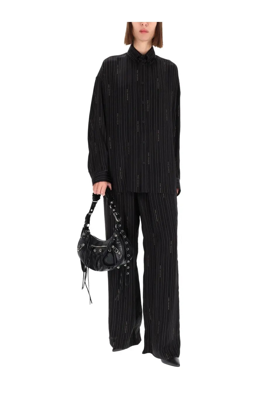Balenciaga black leather crossbody bag with silver hardware and frayed straps shown with women’s pants pyjama black