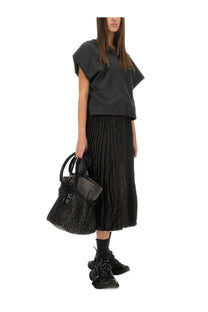 Black textured leather handbag with quilted pattern and top handles accompanying Balenciaga women’s pleated brown skirt