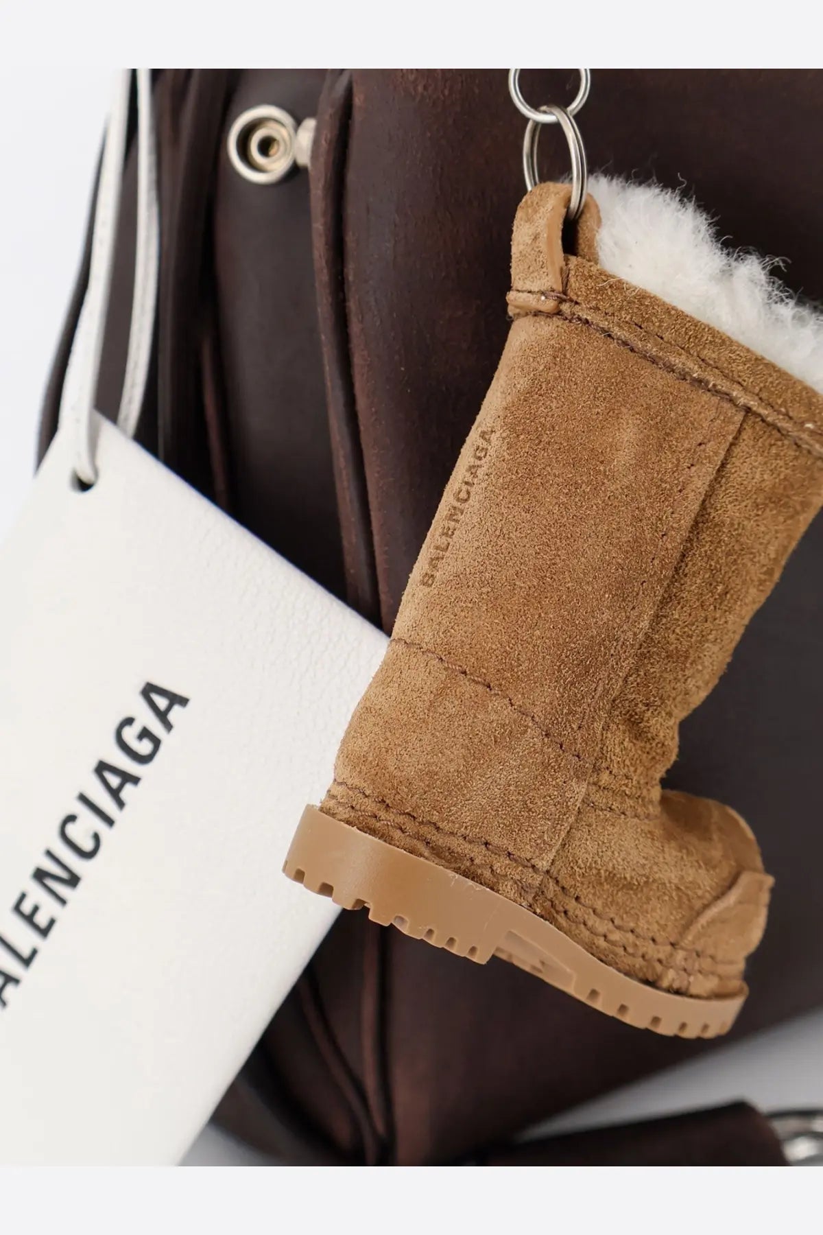 Tan suede boot-shaped keychain with white faux fur lining rubber sole and balenciaga logo for balenciaga rodeo bag